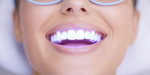 A woman is smiling with bright, illuminated teeth, wearing protective eyewear. Dental care, teeth whitening, oral hygiene