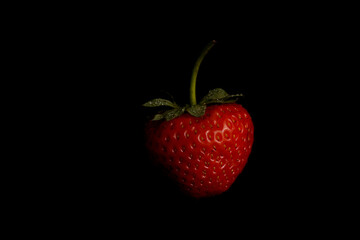 Strawberry with water drops on a black background. Detailed close-up with visible seeds and texture. Natural and sweet fruit for healthy food visuals.

