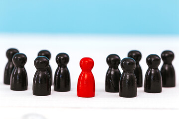 One red pawn standing amidst group of black pawn on blue background for different thinking ideas and leadership concept