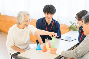 リハビリ施設,介護施設で働く若いアジア人男女スタッフとシニア男女
