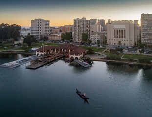 Lake Merritt in Oakland, California, USA, at dusk. A gondola carries passengers on the water near the Lake Chalet restaurant, offering a unique dining experience. © Zenstratus
