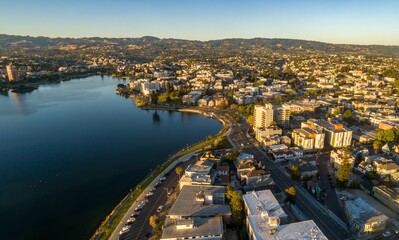 Fototapeta premium Aerial view of Lake Merritt in Oakland, California, USA, at sunrise. The photo shows the lake, the city skyline, and the surrounding hills. The light is golden and warm.