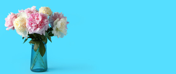 Glass vase with beautiful peony flowers on blue background