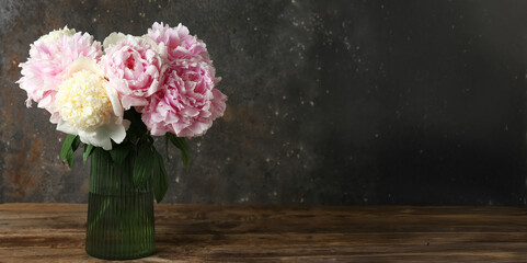 Glass vase with beautiful peony flowers on wooden table