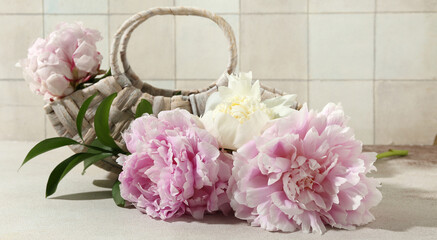 Wicker bag with beautiful peony flowers on white table
