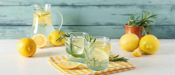 Glasses of fresh lemonade with rosemary and lemons on white wooden table