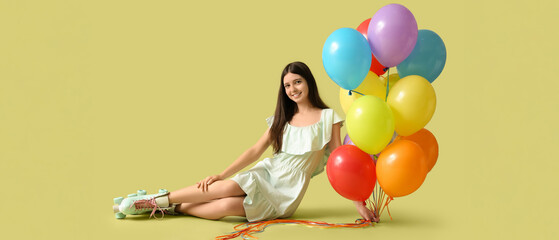 Teenage girl in roller skates and with many balloons sitting on color background