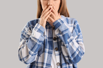 Worried young woman on grey background
