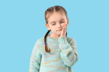 Little girl feeling tooth ache on blue background