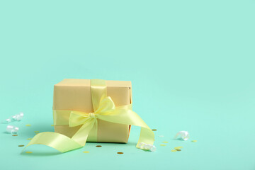 Yellow gift box with serpentine and confetti on turquoise background