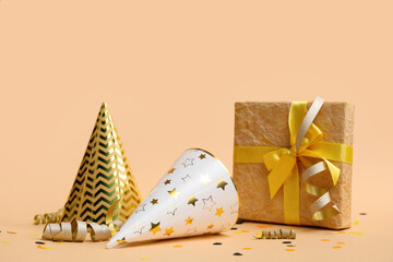 Party hats with gift box and confetti on brown background