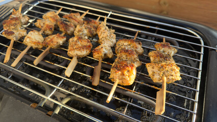 Delicious chicken skewers cooking on an outdoor electric grill