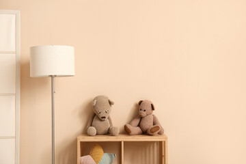 Lamp with toys on commode near beige wall in children's room