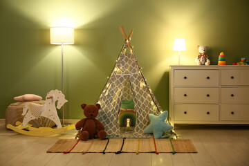 Interior of night children's room with glowing lamps, rocking horse, play tent and toys on commode...