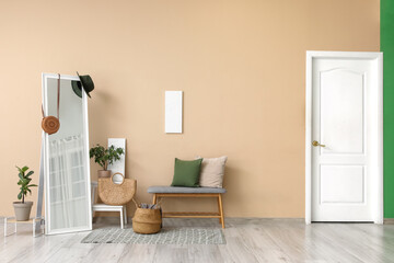 Interior of living room with bench, mirror, houseplants and accessories near beige wall