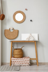 Interior of living room with hanging mirror and home decor on table near grey wall