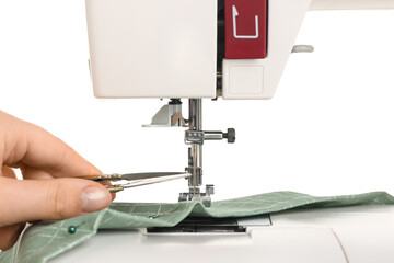Female hand with thread snips and sewing machine on white background, closeup
