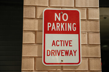 Outdoor sign displayed on brick wall serves as a cautionary message. Text reads 'NO PARKING' and...