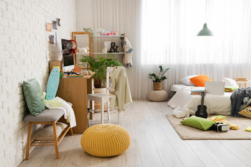 Interior of messy children's room with bed, table and scattered clothes