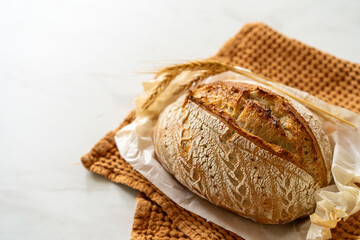 Crispy sourdough bread sits beside a glass jar filled with active starter, accompanied by a rustic...