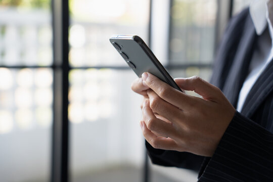 Asian Business woman using smart phone spending time checking news social media - Powered by Adobe