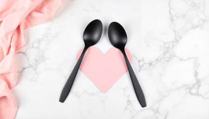 Black spoons arranged in heart shape on marble surface with fabric  