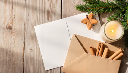 Festive envelope with cinnamon sticks and candle on wooden table  
