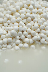 Small white ball shape cheese in a container .