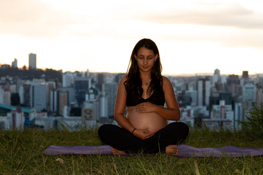 Mulher gr&aacute;vida segurando a barriga no parque