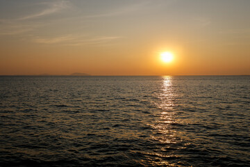 serene sunset view over the ocean, with the sun casting a warm golden reflection