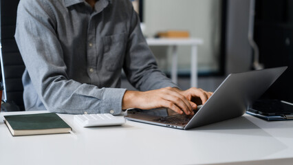 A smart Caucasian businessman sits confidently at desk in modern indoor office, using laptop for online consulting, showcasing professionalism, success, digital expertise in corporate environment.