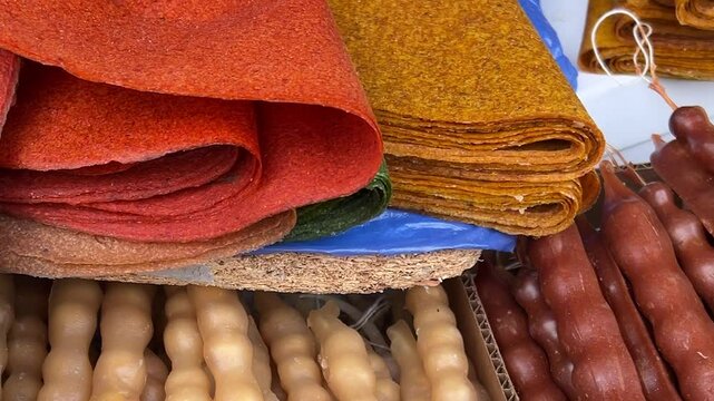 Horizontal video close up. Stall with multicolored georgian dish juicy red churchkhela on street market table. Sweet shop on Tbilisoba fair, harvest holiday, New Year festival. Health food, diet, sale