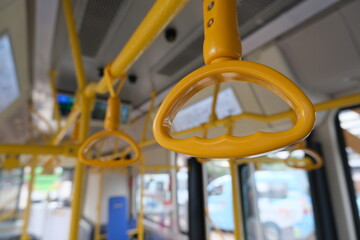 Yellow hand straps inside a public bus, designed for standing passengers to hold onto for stability during the ride.