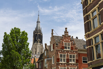 The majestic Nieuwe Kerk spire rises above charming historic Dutch gable houses, a classic scene in beautiful Delft, Netherlands.