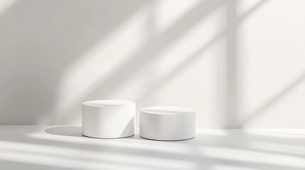 Two white cylindrical podiums in a sunlit room.