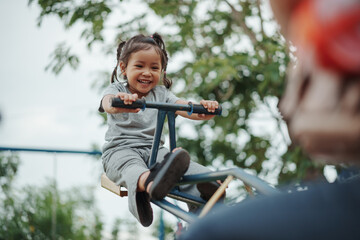 Obraz premium toddler girl playing seesaw in playground