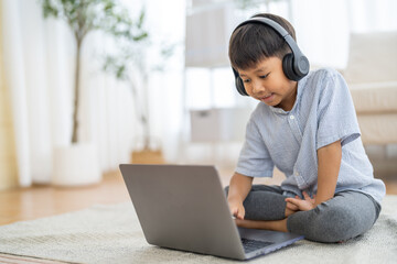 Asian boy using laptop with headphones course online learning, distance education for kids, e-learning at home, child studying digital technology, interactive education platform, remote class tutorial