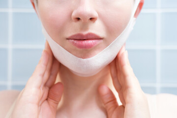 Portrait of a young woman with a mask for double chin front view close-up on blue background.