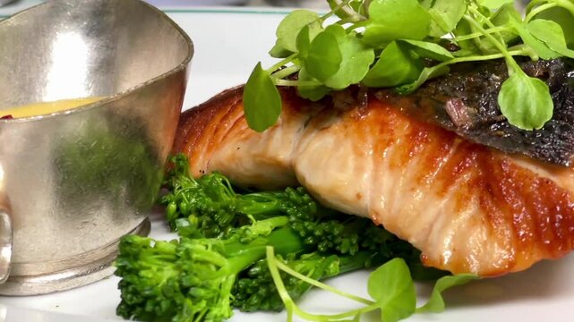 Salmon fillet with crisp skin, served with tenderstem broccoli, microgreens and creamy peppercorn sauce in London, slow motion