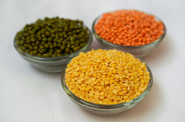 Moong or mung, boot Chana, chickpea pea, yellow, red, green dal lentil pulse bean split verity. Selective focus on golden moong dal, isolated on white background.