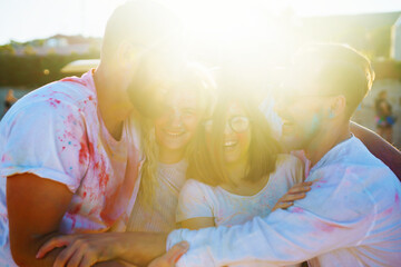 A happy group of friends having fun at the Holly festival on the sunset beach. Young men and women...