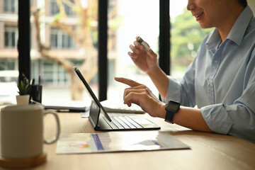 Close-up of a businessman holding a credit card and using a tablet for an online transaction at a modern workspace