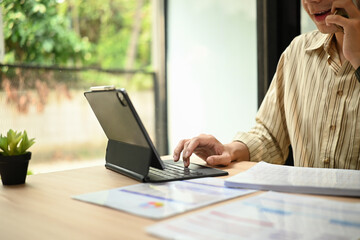 A close-up image of a Remote worker multitasking between a phone call and digital work during...