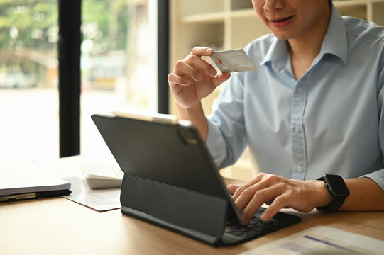 Close-up of businessman inputting payment details on a tablet with credit card in hand