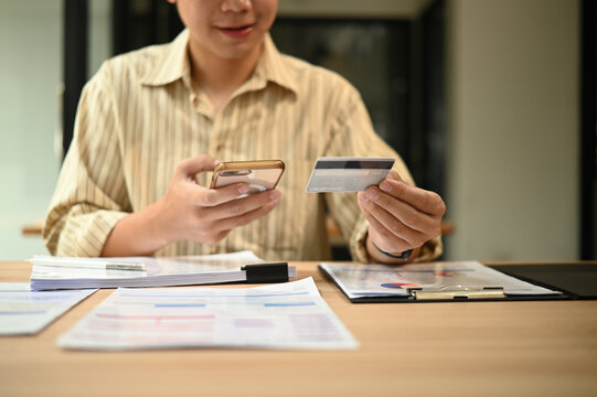 Close-up image of a young businessman using smartphone and credit card at work desk, Mobile Payment and Online Finance