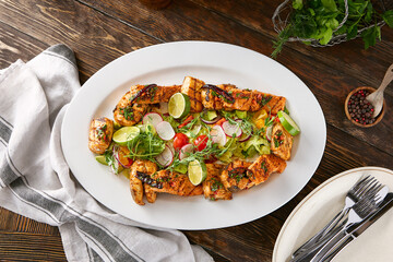 Grilled fish assortment with lime and vegetables, rustic lighting, overhead composition