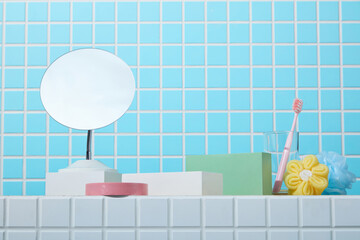 Toothbrush, soap, and pastel skincare on bathroom shelf with blue mosaic tile wall and round...