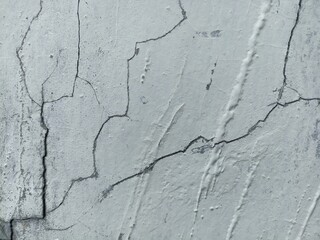 Cracked White Concrete Wall Texture. Close-up of a white painted concrete wall with visible cracks...