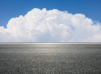 Empty asphalt road and blue sky with white cumulus clouds on a sunny day