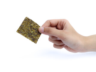Hand holding a square sheet of roasted seaweed snack against a white background.